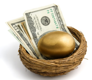gold egg sitting atop a stack of bills with a one hundred dollar bill on top. shot on white